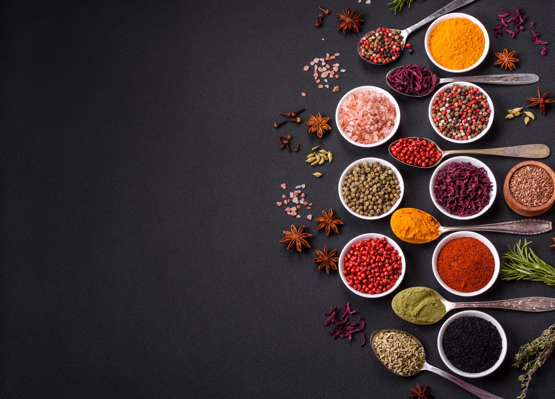 Composition consisting of variations of spices in white bowls and metal spoons