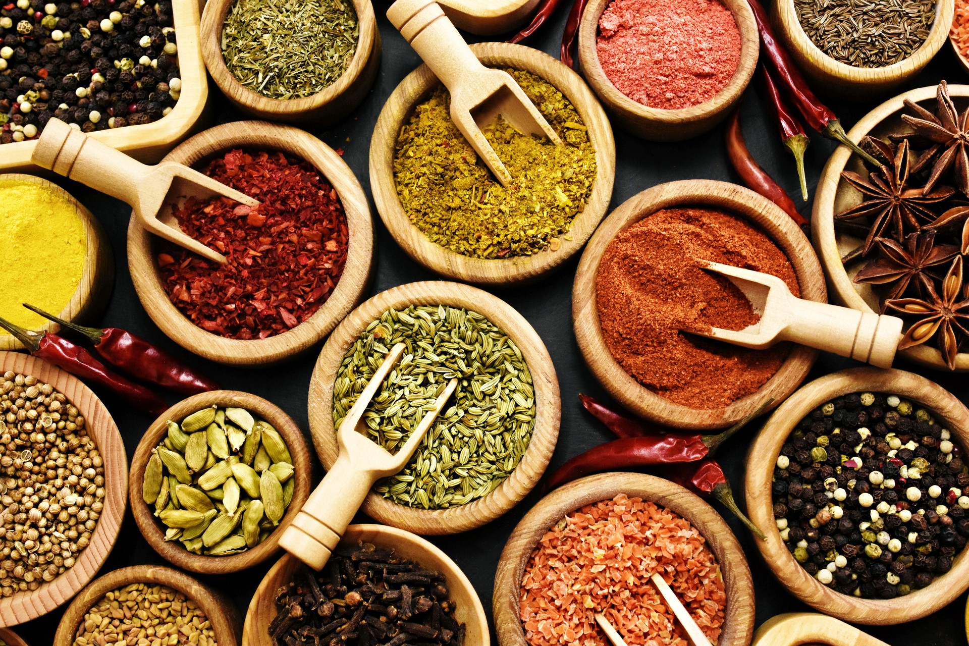 Colorful mix of herb and spice varieties: curry and coriander, turmeric and cumin, paprika and pepper, mustard and salt, cardamon and oregano and saffron